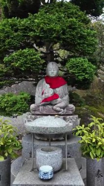 Geleneksel Japon Tapınağı Bahçesi 'nde kırmızı önlüklü barışçıl Jizo heykeli. Yüksek kalite 4k görüntü