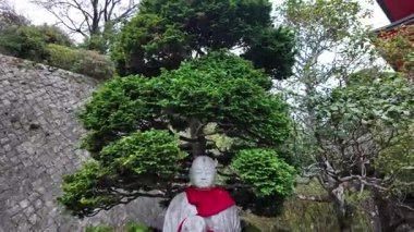 Geleneksel Japon Tapınağı Bahçesi 'nde kırmızı önlüklü barışçıl Jizo heykeli. Yüksek kalite 4k görüntü