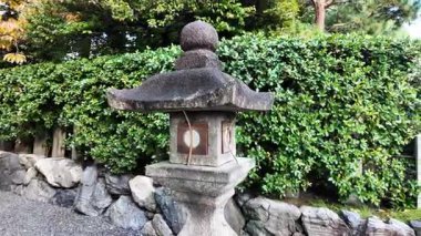 Huzurlu bir Japon bahçesindeki Yeşil Bitkilerle çevrili bir göl tarafından çevrelenmiş Stone Garden Feneri. Yüksek kalite 4k görüntü