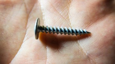 Elinde parlak metal bir vidanın makro çekimi