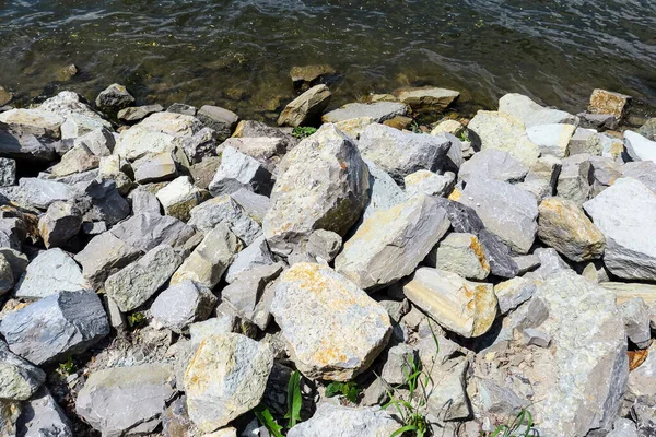 Stones near the water on the shore of the pond