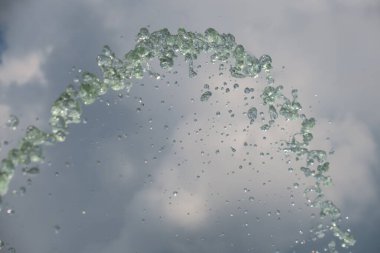 Gökyüzünün arka planındaki çeşmeden fışkıran su.