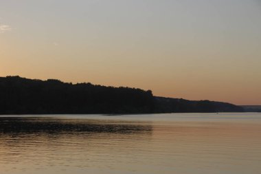 Gün batımı göletteki suda parlıyor.