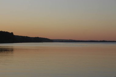 Gün batımı göletteki suda parlıyor.