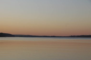 Gün batımı göletteki suda parlıyor.