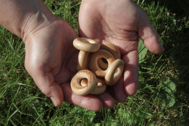 Yeşil arka planda ellerinde hamur olan sarı simit.