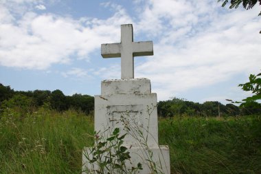 Beyaz çimlerin üzerinde beyaz beton bir Hıristiyan haçı