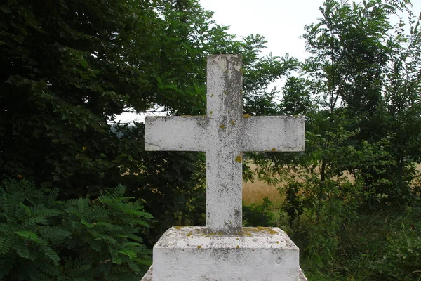 白色混凝土基督教十字架在草地背景下的田野里 — 图库照片