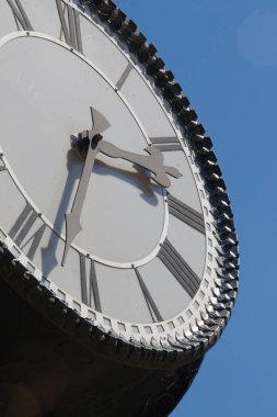 Parktaki bir sokak saatinin metal kadranı ve sandalyeleri