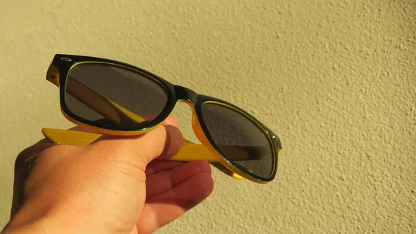 Yellow-black sun protective goggles in hand