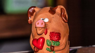 Oyuncak gözlü domuz, kilden yapılmış, çiçek ve kalpten.