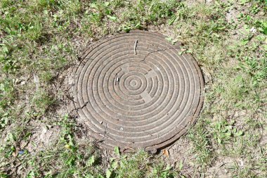 Metal manhole in the park in August