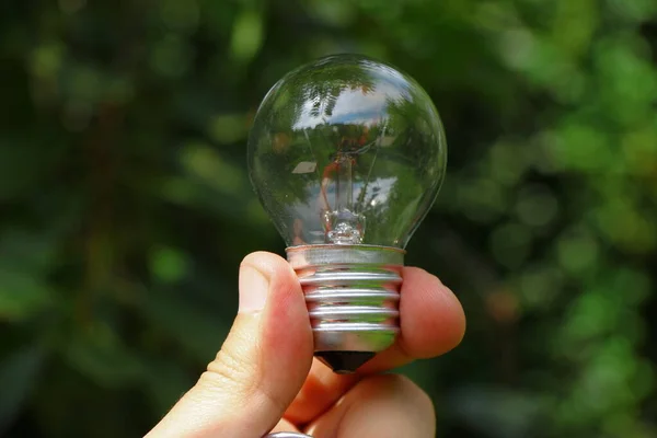 Non-working glass incandescent lamp in hand