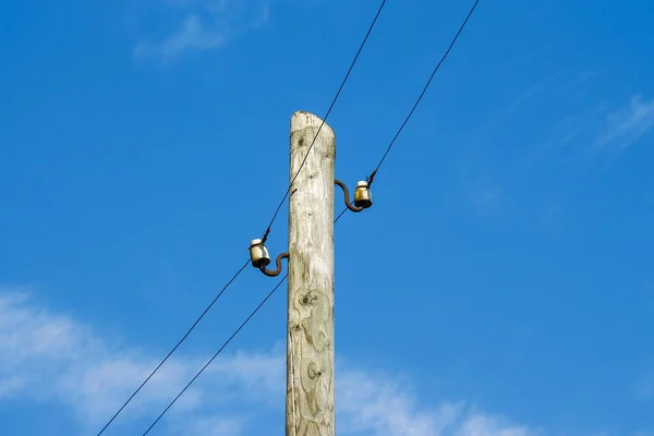 Wooden pole with radio transmission lines on sky background