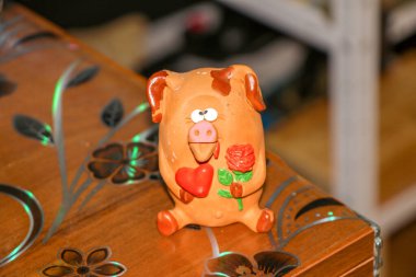 Bir çiçeğe aşık şaşı gözlü domuz yavrusu ve pençelerinde kırmızı bir kalp Sevgililer Günü 'nü ve 8 Mart Sevgililer Günü' nü, Anneler Günü 'nü kutluyor.