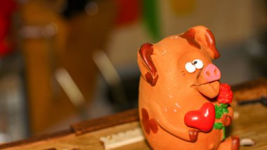 Bir çiçeğe aşık şaşı gözlü domuz yavrusu ve pençelerinde kırmızı bir kalp Sevgililer Günü 'nü ve 8 Mart Sevgililer Günü' nü, Anneler Günü 'nü kutluyor.