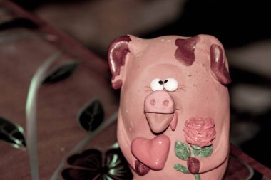 Bir çiçeğe aşık şaşı gözlü domuz yavrusu ve pençelerinde kırmızı bir kalp Sevgililer Günü 'nü ve 8 Mart Sevgililer Günü' nü, Anneler Günü 'nü kutluyor.