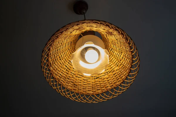 Beautiful lamp on the ceiling with a wooden wicker lampshade