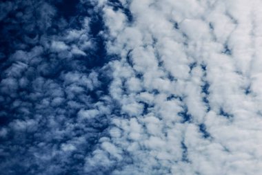 Mavi gökyüzü ve güneşli havada beyaz bulutlar.