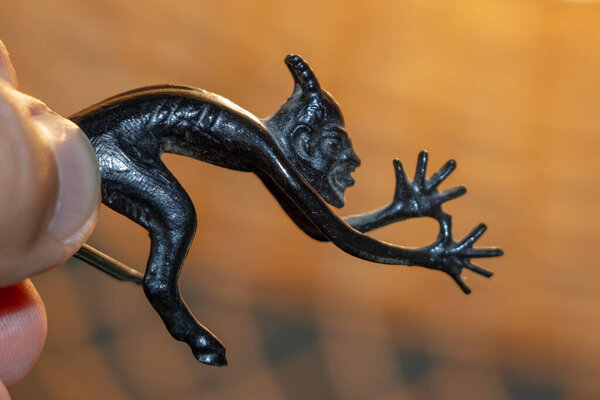 A small metal sculpture of the devil with a tail showing his tongue