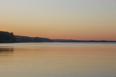 Gün batımı göletteki suda parlıyor.