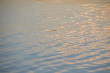 Gün batımı göletteki suda parlıyor.