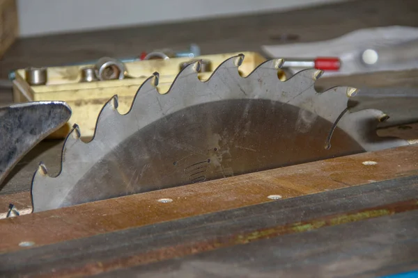 A large shiny metal saw on a circular saw in the workshop
