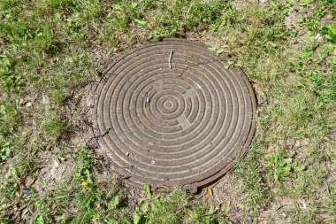 Metal manhole in the park in August