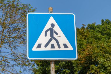 Yol kenarında yaya geçidi işareti var.