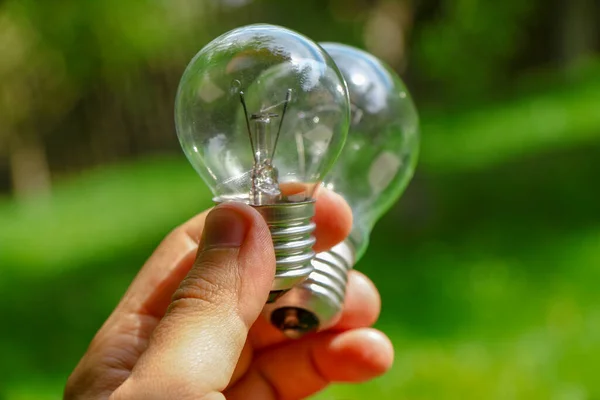 白熱電球の電力100ワット 手に電球の色の背景 — ストック写真