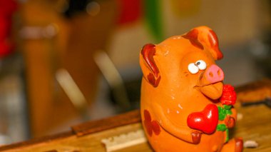 Bir çiçeğe aşık şaşı gözlü domuz yavrusu ve pençelerinde kırmızı bir kalp Sevgililer Günü 'nü ve 8 Mart Sevgililer Günü' nü, Anneler Günü 'nü kutluyor.