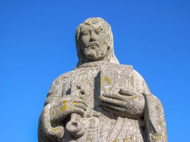 Elinde İncil olan Hristiyan bir azizin taş anıtı.