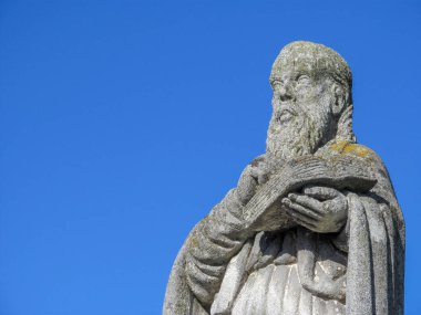 Elinde İncil olan Hristiyan bir azizin taş anıtı.