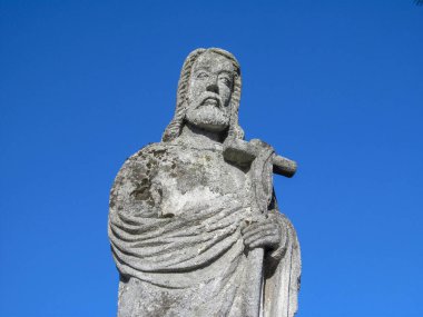 Elinde haçla bir azizin taş anıtı.