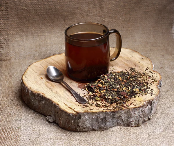 Chá preto com ginseng, gengibre, com a adição de maçãs, canela, cardamomo, cravo, erva de São João, casca de limão, pimenta preta, visco, satisfazendo Rooibos e crostas feijão e capim-limão. em uma caneca em um suporte de madeira, à base de plantas — Fotografia de Stock