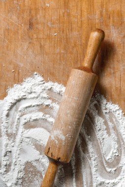 Tahta masaya saçılmış buğday unu. Undan yapılan aşçılık ürünlerinin hazırlanması. Tahta zemin üzerinde duran beyaz un ve oklavanın üst görüntüsü. Yazıt için bir yer var..