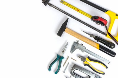 Aletler ve parçalar beyaz arkaplanda. Metal nesne. Bir grup tamir aleti. Çeşitli parçalar ve yedek parçalar masanın üzerinde. Erkekler için aletler. Bir takım çalışma araçları.