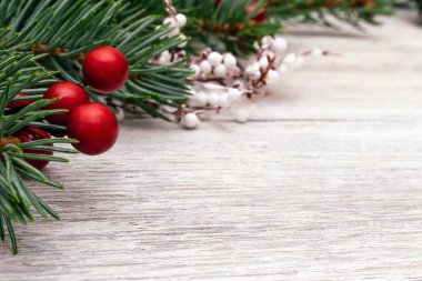 Beyaz ahşap arka planda köknar ağacı dalları, beyaz dallar ve kırmızı böğürtlenlerden yapılmış Noel çerçevesi. Noel, kış arkaplanı. Yazı için kopyalama alanı, düzlük.