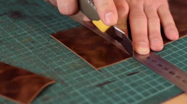 Tanner 'ın ellerine yaklaş ve deriyi bıçakla kes. El yapımı deri ürünleri. Hobi konsepti. Yavaş çekim.