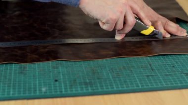 Tanner 'ın ellerini bıçakla ölçüp keserek yakın çekim yapın. El yapımı deri ürünleri. Hobi anlayışı..