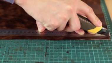 Tanner 'ın ellerini bıçakla ölçüp keserek yakın çekim yapın. El yapımı deri ürünleri. Hobi anlayışı..