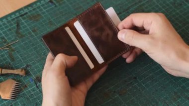 Gerçek deriden yapılmış ürünler üretme süreci. Tamamlanmış deri kart sahibinin tanıtımı. Hobi konsepti. Yavaş çekim, yakın çekim..