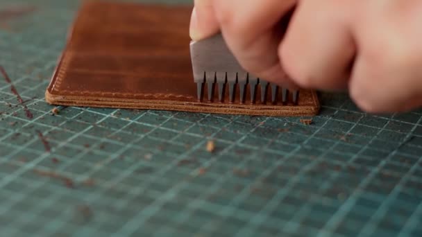 革のカードホルダーを製造するプロセス金属製のパンチャーで作品に穴を開ける 手作りの革製品 趣味のコンセプト — ストック動画