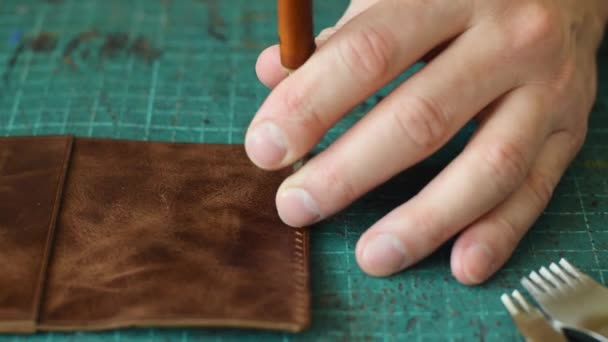 皮革制卡机的制造过程 用金属冲孔在皮革工件上打孔 手工制作的皮革制品 哈比人的概念 工匠的手特写 动作缓慢 — 图库视频影像