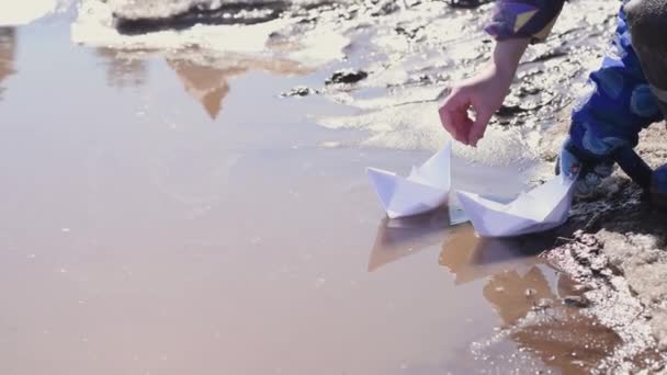 Kinder Werfen Papierboote Eine Schlammige Frühlingspfütze Frühlingskonzept Kinderfreizeit Nahaufnahme Zeitlupe — Stockvideo