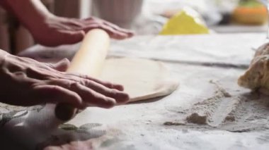 Bir kadın hamuru oklavayla çeviriyor. Eller yukarı, yavaş çekimde..