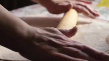 Bir kadın hamuru oklavayla çeviriyor. Eller yukarı, yavaş çekimde..