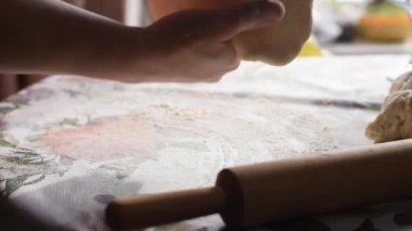 Bir kadın hamuru oklavayla çeviriyor. Eller yukarı, yavaş çekimde..