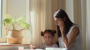 Koyu renk saçlı, melez bir kadın, çizim yapan kızına hayran. Aile kavramı. Birlikte olma zamanı..