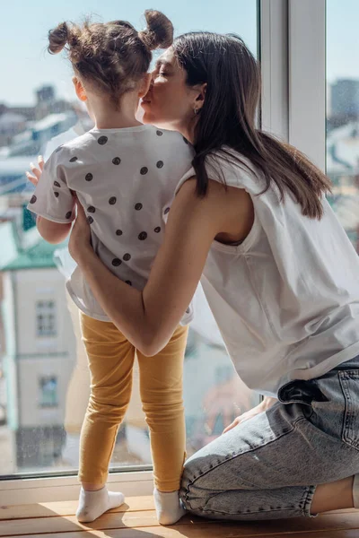 Ung Mörkhårig Kvinna Och Hennes Lilla Dotter Tittar Genom Fönstret — Stockfoto